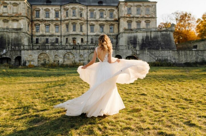 a bride in a white wedding dress in front of an old mansion