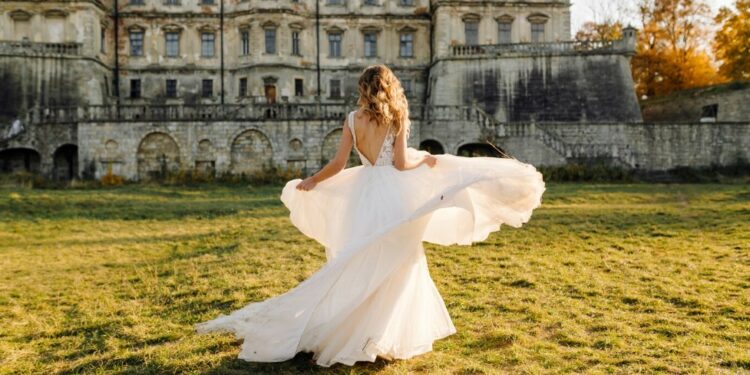 a bride in a white wedding dress in front of an old mansion