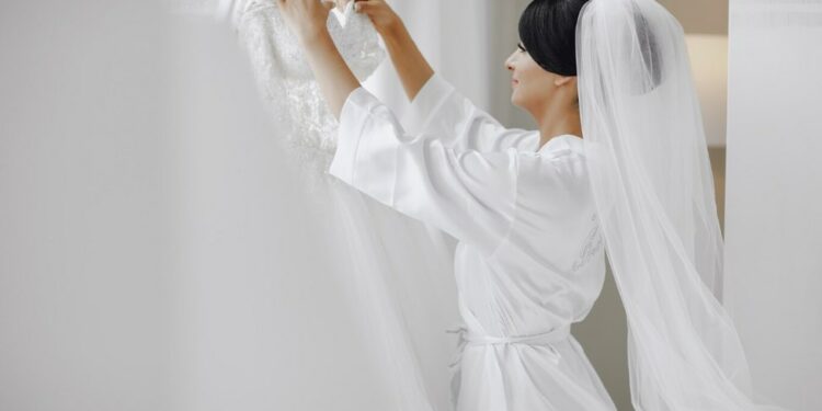 a young brunette bride preparing her wedding dress for the ceremony