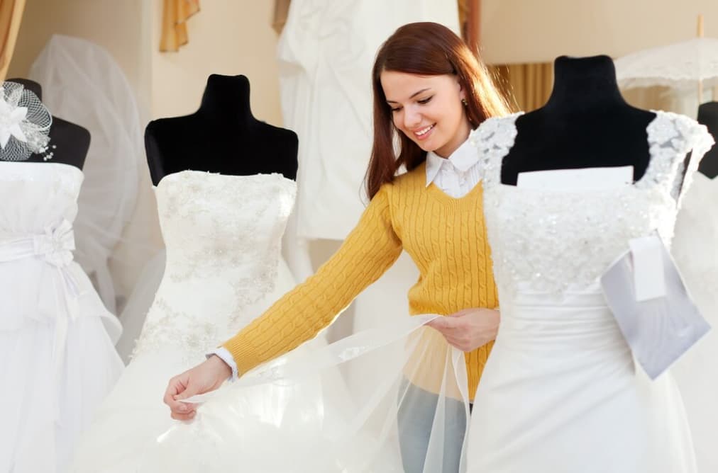A woman examines a wedding dress in a bridal shop
