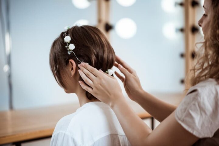 Hairstylist adorning a bride's hair with white floral accessories