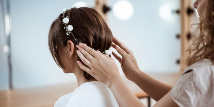 Hairstylist adorning a bride's hair with white floral accessories