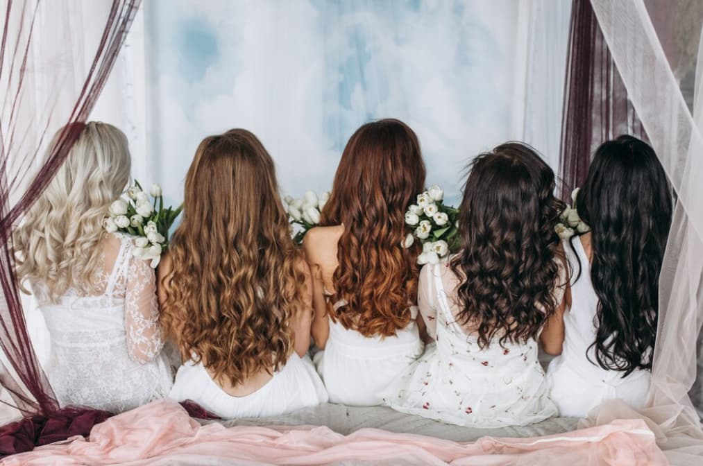 Four bridesmaids with floral hair decorations looking out a window