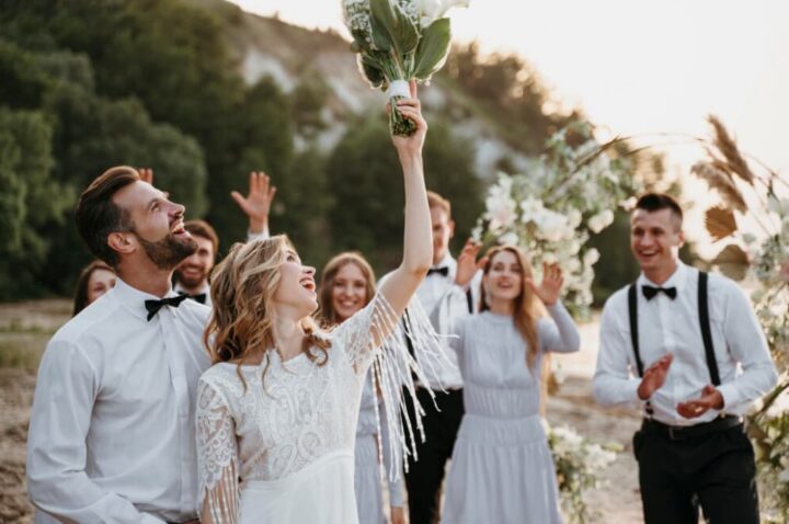 Bride joyfully tosses her bouquet to guests at an outdoor wedding