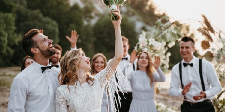 Bride joyfully tosses her bouquet to guests at an outdoor wedding