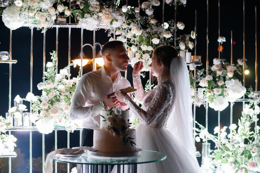 Newlyweds share a romantic moment amidst a floral wedding backdrop at night
