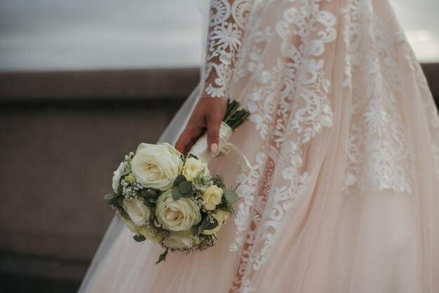 The bride is wearing a beautiful wedding dress and holding a bouquet of beautiful roses