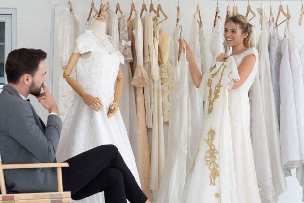 The groom helps his wife choose a wedding dress