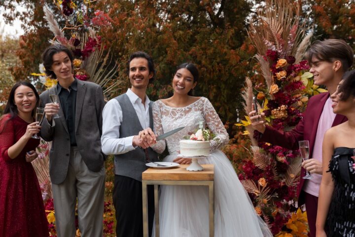 Smiley groom and bride with guests cut wedding cake