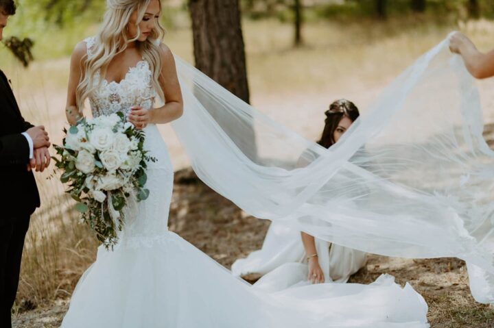 Bride in white dress and long veil with flowers in her hands