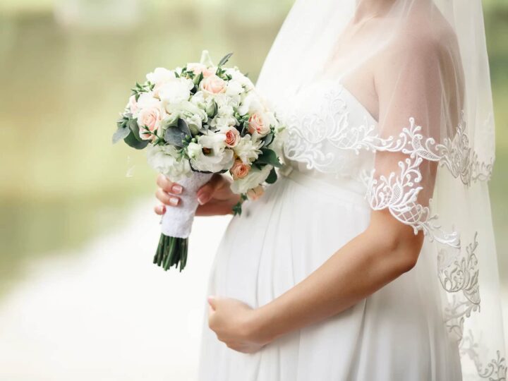 Pregnant bride with a bouquet in hand