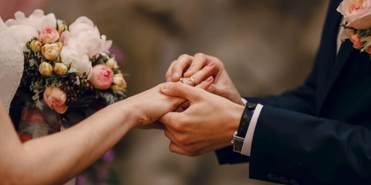 Groom putting ring on bride's finger