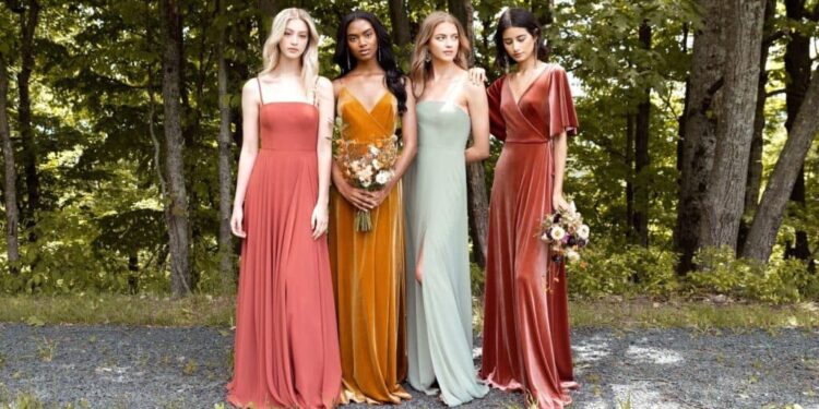 Several girls in dresses stand against the background of trees