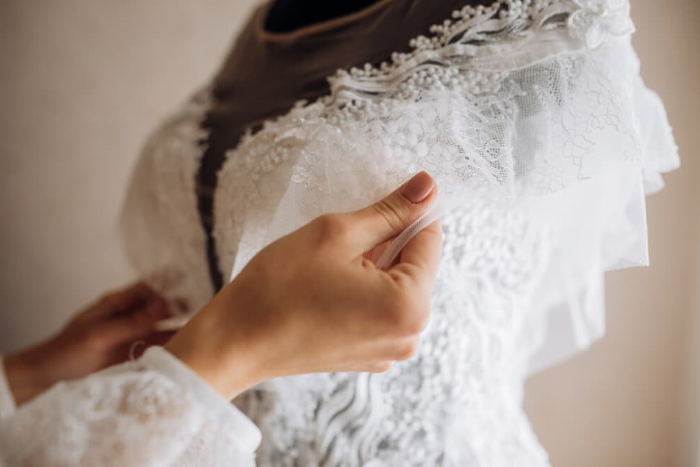hand touches the wedding dress on the mannequin