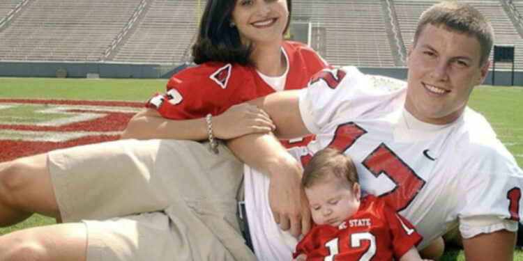 A family in sports jerseys on a football field, with a baby in a miniature jersey