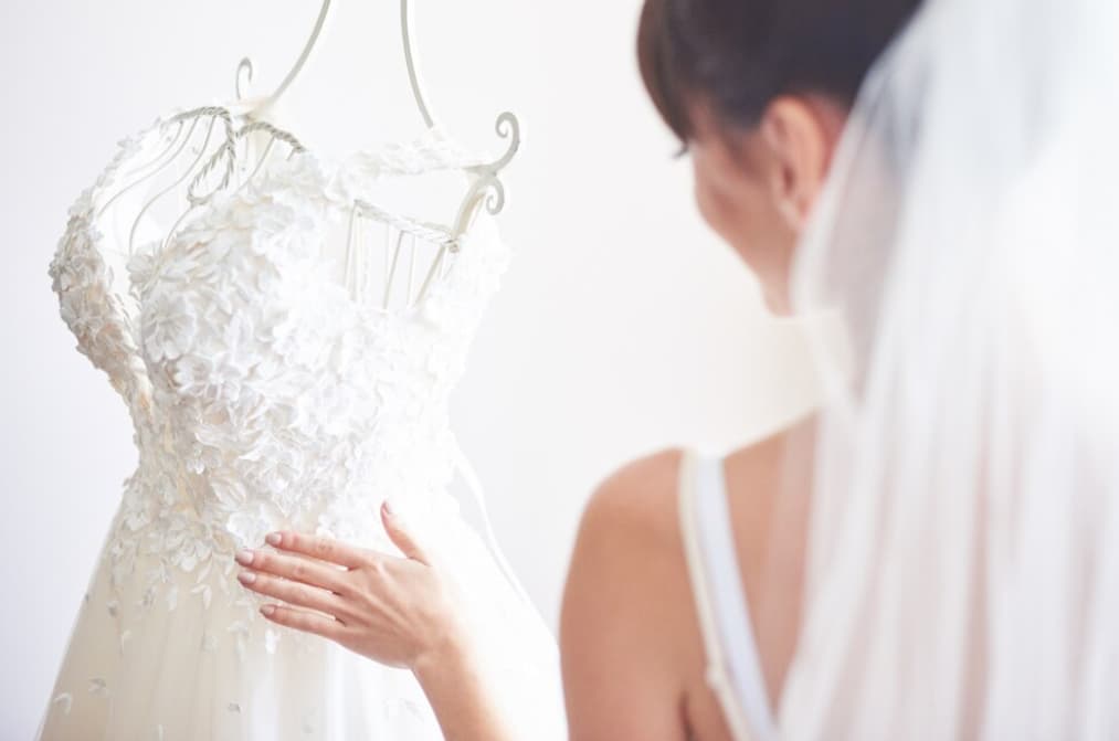 A woman in a sleeveless top reaching out to a hanging wedding dress