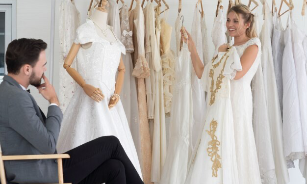 The groom helps his wife choose a wedding dress