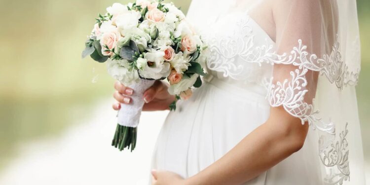 Pregnant bride with a bouquet in hand